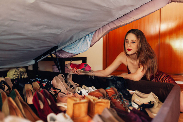 Teenager zeigt ihre große Kollektion von Schuhen, Turnschuhen und Absätzen. - Foto, Bild