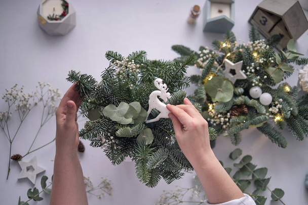 woman decorates a Christmas arrangement. Hands close-up. The new year celebration. Flower shop. Table decorations, floral composition. - Foto, Imagem