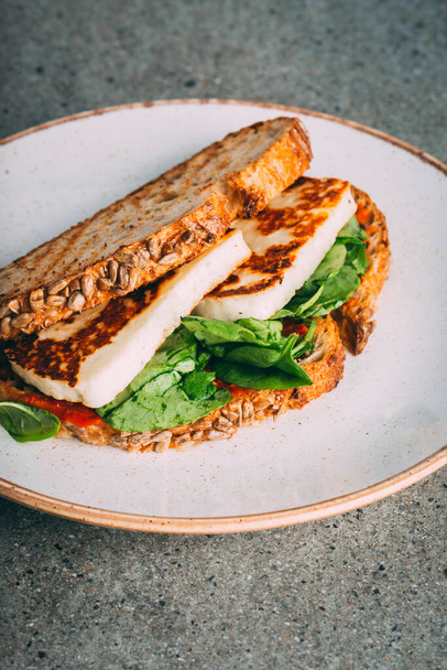 A vertical shot of a gourmet sandwich with fried tofu and spinach - Fotó, kép