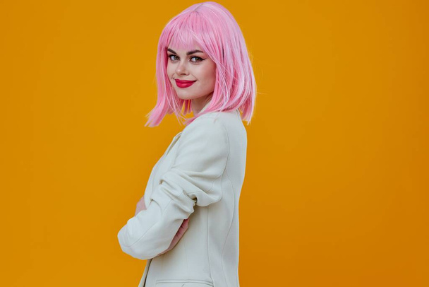 Woman in white suit pink wig posing on yellow background - Photo, Image