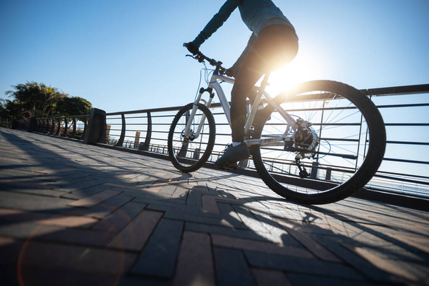 Woman riding bike at city on sunny day - Foto, Bild