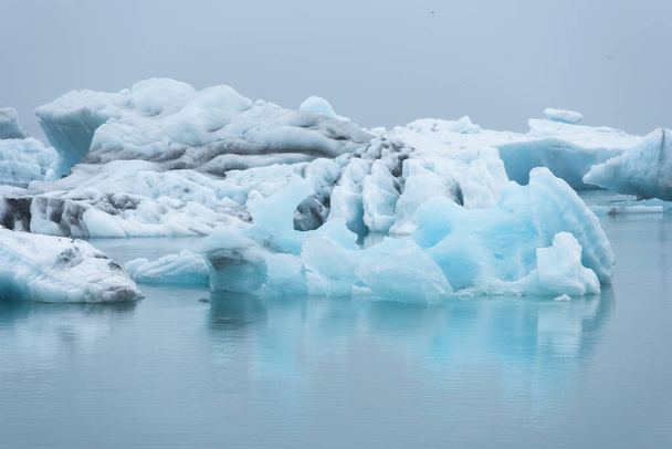 Melting icebergs as a result of global warming and climate change floating in Jokulsarlon glacial lagoon. Vatnajokull National Park, Iceland - Фото, изображение
