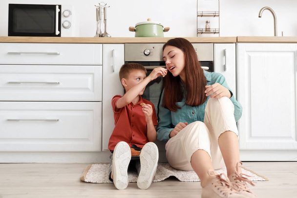 Little boy and his older sister eating tasty cookies in kitchen - Foto, Imagen