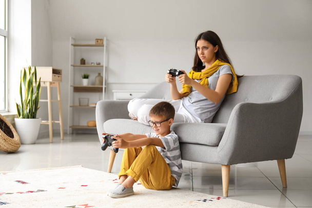 Niño pequeño con su hermana mayor jugando videojuegos en casa - Foto, imagen