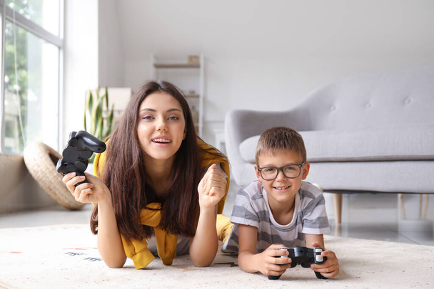 Kisfiú a nővérével videojátékot játszik otthon a padlón. - Fotó, kép