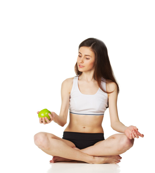 Girl in lotus position holds apple - Foto, immagini