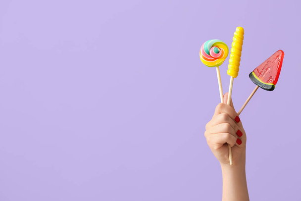 Woman holding lollipops on lilac background - Photo, Image