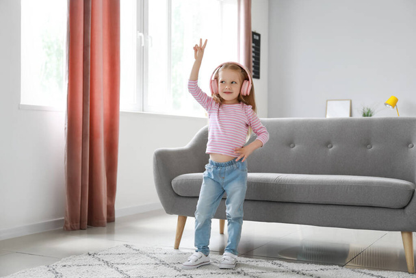 Χαριτωμένο κοριτσάκι με ροζ ακουστικά που χορεύει στο σπίτι - Φωτογραφία, εικόνα