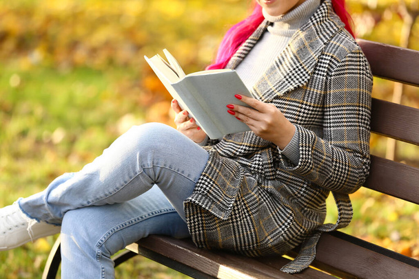 Красивая женщина читает книгу о скамейке в осеннем парке
 - Фото, изображение