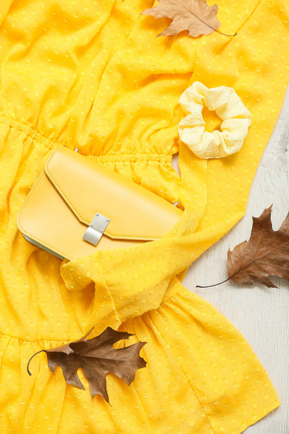 Стильна сукня, скручування, сумка та осіннє листя на світлому дерев'яному фоні
 - Фото, зображення