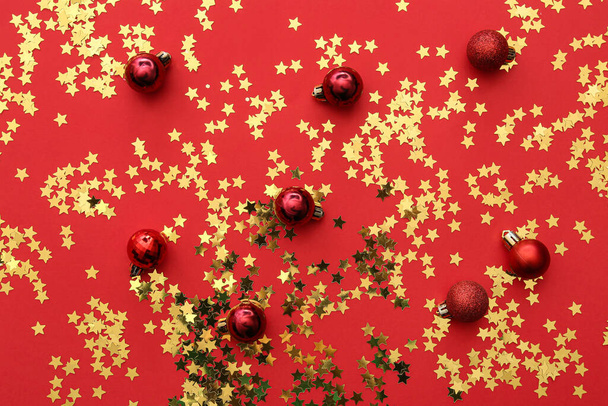 Golden confetti with Christmas balls on red background - Valokuva, kuva
