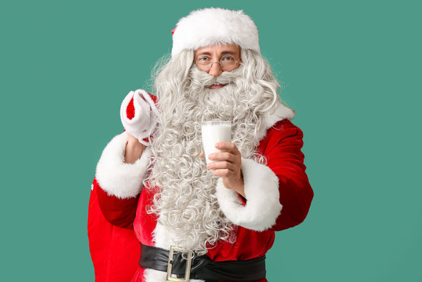 Kerstman met glas melk en zak op groene achtergrond - Foto, afbeelding