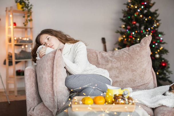 Young woman feeling alone during christmas holiday. Frustrated depressed sad sick teen girl sitting on sofa at hom - Fotoğraf, Görsel