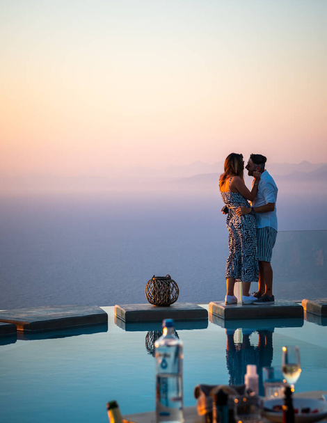 Lefkada sziget. Görögország - 08.07.2021: egy fiatal pár élvezi a romantika és a medence oldalán finom étkezési fantasztikus kilátás nyílik a tengerre. - Fotó, kép