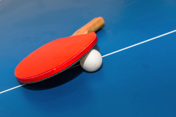 Lapát, teniszlabda a kék ping-pong asztal közel.Kék asztalitenisz vagy ping-pong.Szelektív fókusz.Szoros. - Fotó, kép