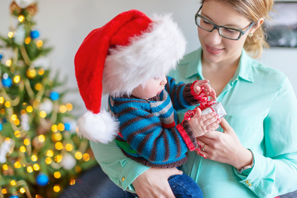 Lindo bebé abriendo un regalo de su madre
 - Foto, Imagen