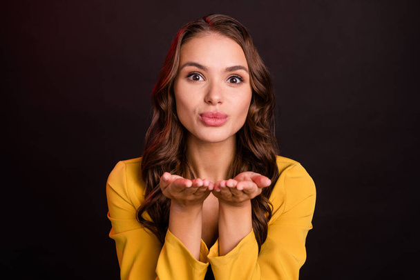 Photo of lovely young brunette lady blow kiss wear yellow jacket isolated on dark color background - Zdjęcie, obraz