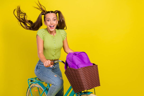 Portrait of pretty funny cheerful girl riding bike good mood having fun isolated over bright yellow color background - Zdjęcie, obraz