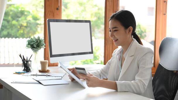Egy sikeres női vállalkozástulajdonos vagy ügyvezető igazgató ül az irodájában, és pénzt utalnak át online alkalmazással. hitelkártya-koncepció. - Fotó, kép