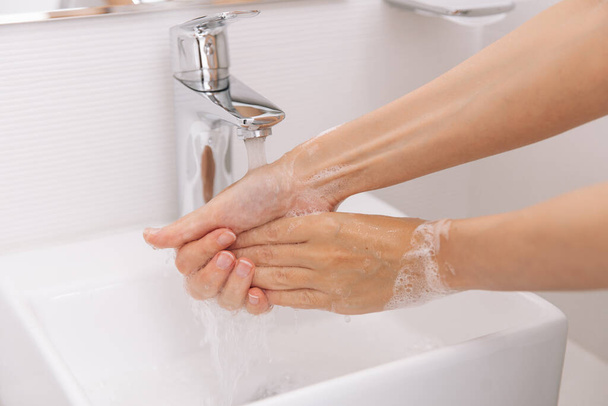 Washing hands under the flowing water tap. Washing hands rubbing with soap for corona virus prevention, hygiene to stop spreading corona virus in or public wash room. Hygiene concept hand detail - Photo, image