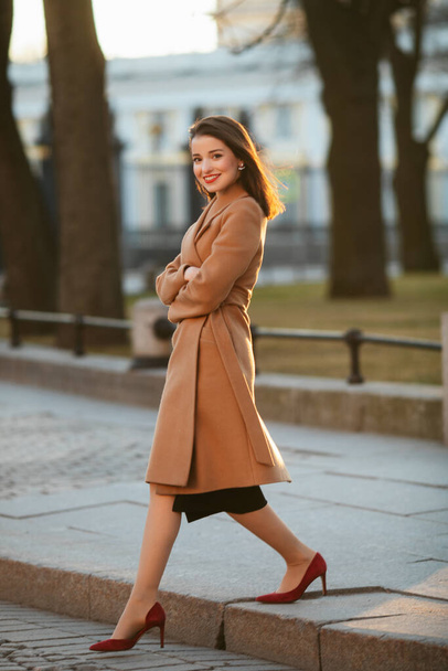 girl in coat in the street at sunrise - Фото, изображение