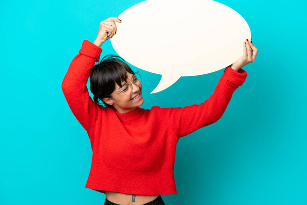 Young woman isolated on blue background holding an empty speech bubble - Photo, Image