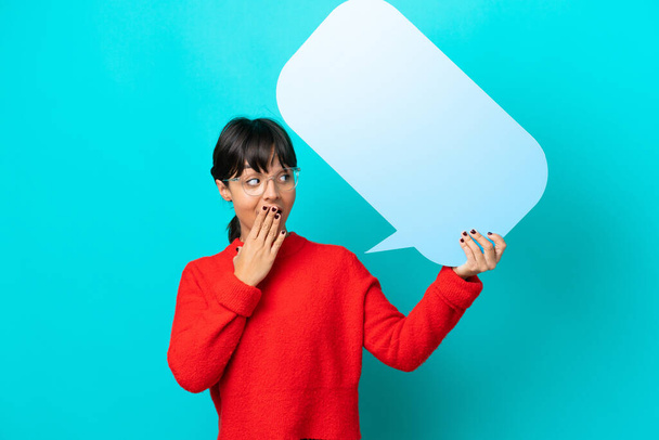 Young woman isolated on blue background holding an empty speech bubble with surprised expression - Fotoğraf, Görsel