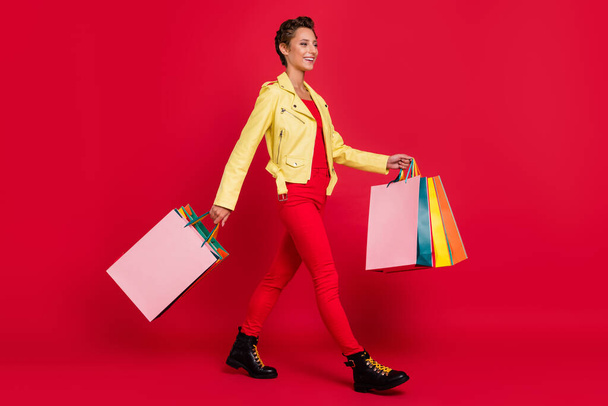 Full size photo of joyful happy woman look go shopping empty space wear casual outfit isolated on red color background - Photo, Image