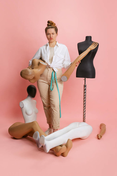One pretty woman, seamstress tailor and parts of mannequin isolated on pink background. Concept of job, hobby - Fotografie, Obrázek