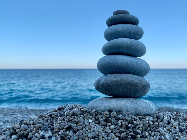 Tema marino: piedras en la orilla. Las piedras se apilan en una pirámide sobre el fondo del mar. Pirámide de pequeñas piedras en la playa. El concepto de armonía de equilibrio y meditación. - Foto, Imagen