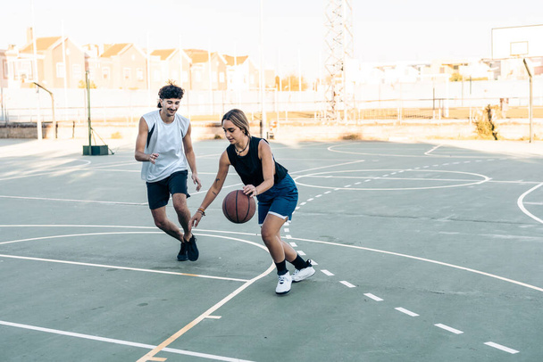 Amigos jugando baloncesto al atardecer en un patio urbano - Foto, imagen