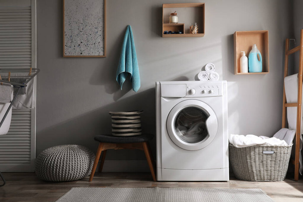 Laundry room interior with modern washing machine near light wall - Фото, изображение