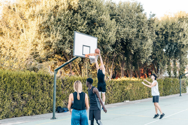 Высокий человек забил гол во время баскетбольного матча на открытой площадке - Фото, изображение