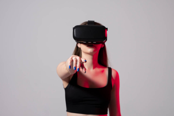 Woman enjoying a VR experience. Woman with VR headset touching invisible screen. Future technology concept. - Foto, Imagen