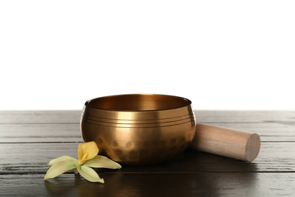 Golden singing bowl, mallet and flower on wooden table against white background - Foto, Imagem