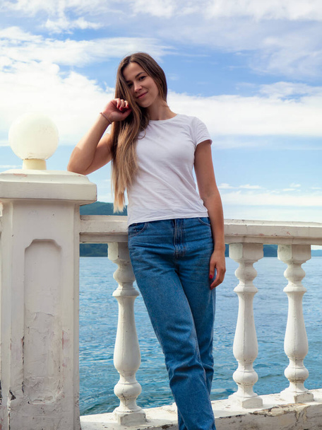 Photo of a girl leaning on the embankment parapet. The photo was taken on a clear summer day. - Foto, imagen