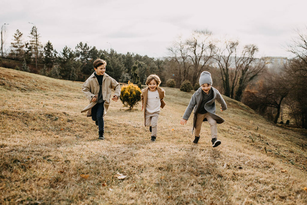 Niños jugando al aire libre en un parque en el día de otoño, corriendo y riendo. - Foto, imagen