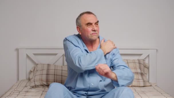 Een oudere man in bed lijdt aan ernstige pijn. Begrip thuisziekte - Video