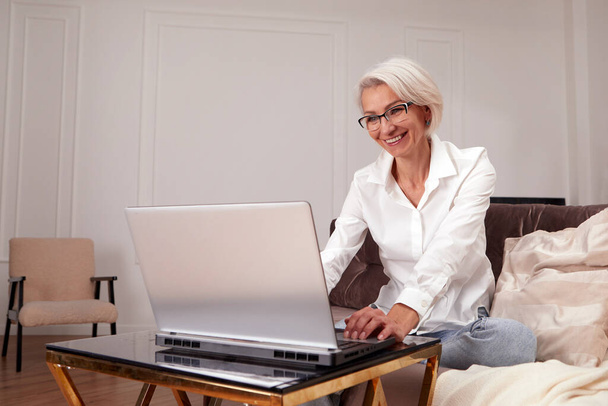 Adult cheerful woman working on laptop at home - Fotoğraf, Görsel