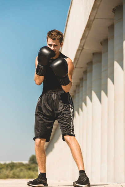 Man exercising and fighting in outside, boxer in gloves. male boxer portrait - Foto, imagen
