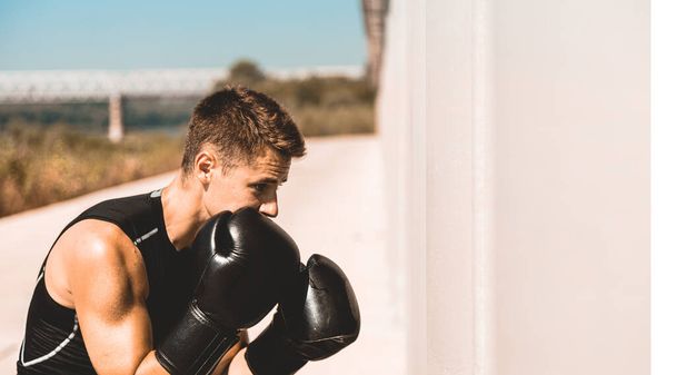 Man exercising and fighting in outside, boxer in gloves. male boxer portrait - Fotoğraf, Görsel