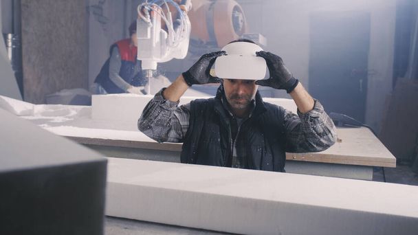 Uomo con auricolare VR esaminando blocco polimero - Foto, immagini
