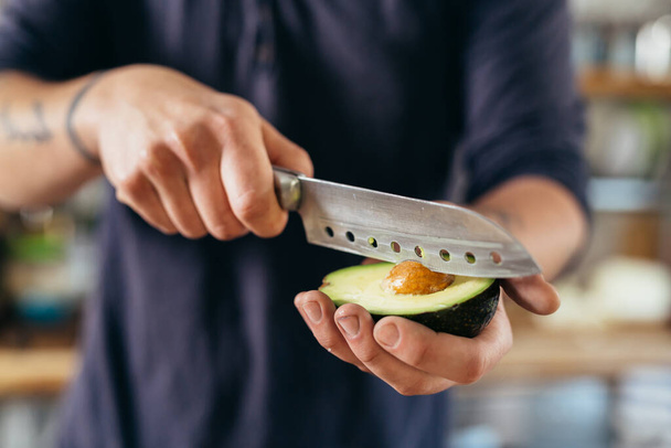 close up man holding knife and avocado - Foto, Bild