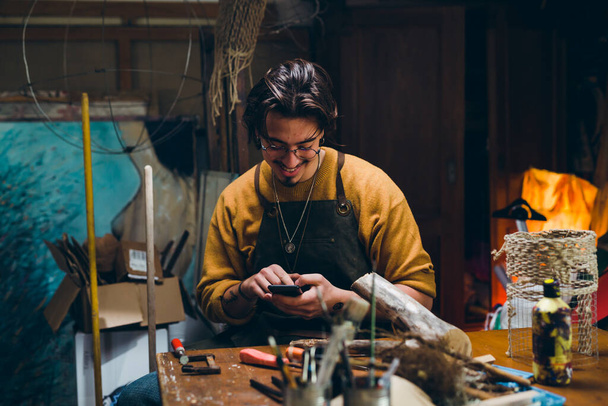 man using smartphone in his workshop - Photo, Image