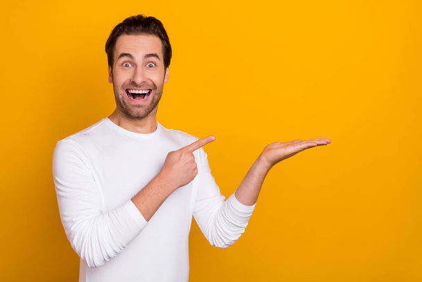 Photo of astonished impressed person finger indicate hand palm empty space isolated on yellow color background - Foto, Imagem