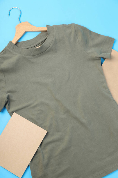 Camiseta en blanco, bolsa y hoja de cartón sobre fondo azul - Foto, Imagen