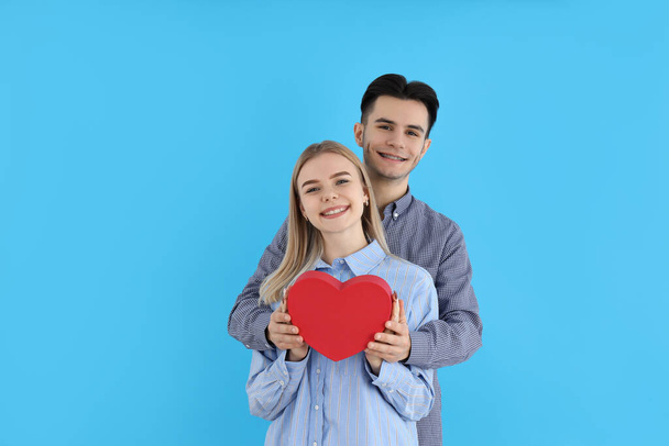 Cute couple holds heart on blue background - Photo, Image