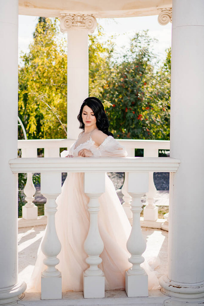 bride in wedding clothes at railing in gazebos or rotunda in the park. - Zdjęcie, obraz