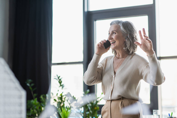 Cheerful businesswoman talking on cellphone in office  - Photo, Image