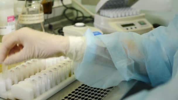 Wetenschapper werkzaam in steriel genetica laboratorium met pipet in medische kamerjas. Coronavirusanalyse. Laboratorium voor Medische Ontwikkeling. Testbuis vullen met vloeibaar, het uitvoeren van experiment. DNA - Video